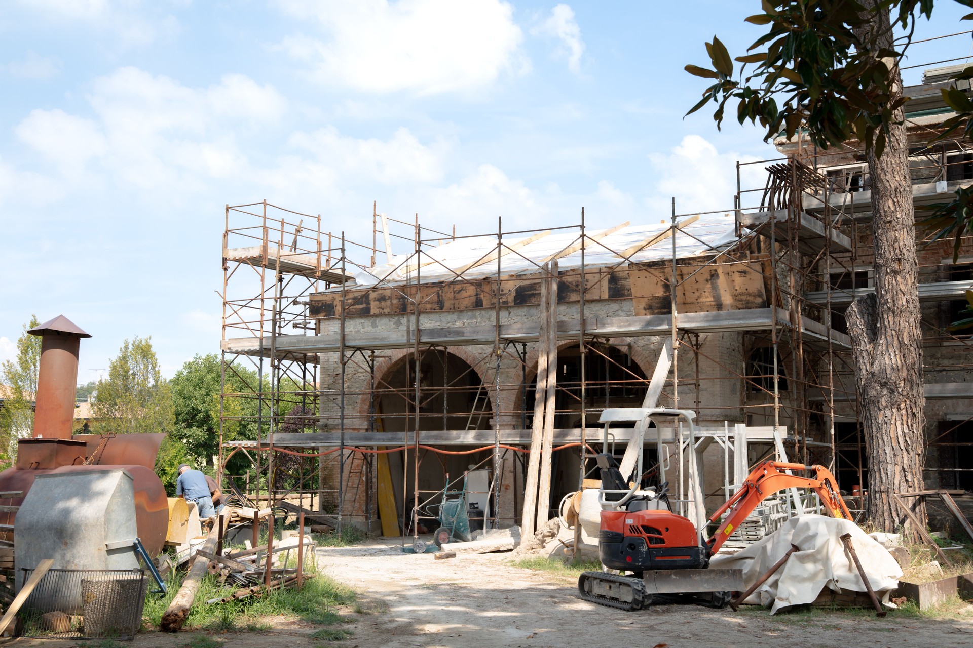 Construction site of a mediterranean historic home renovation with brick house surrounded by scaffolding