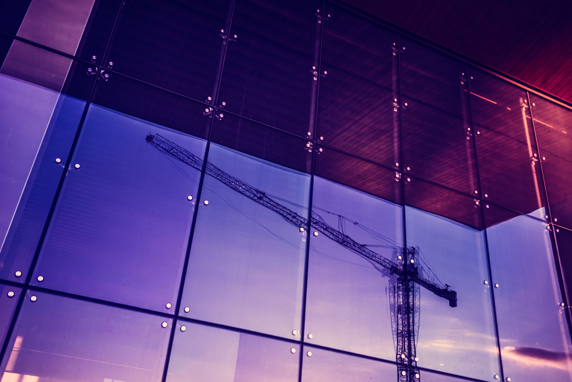 Construction crane reflected into a newly built office building